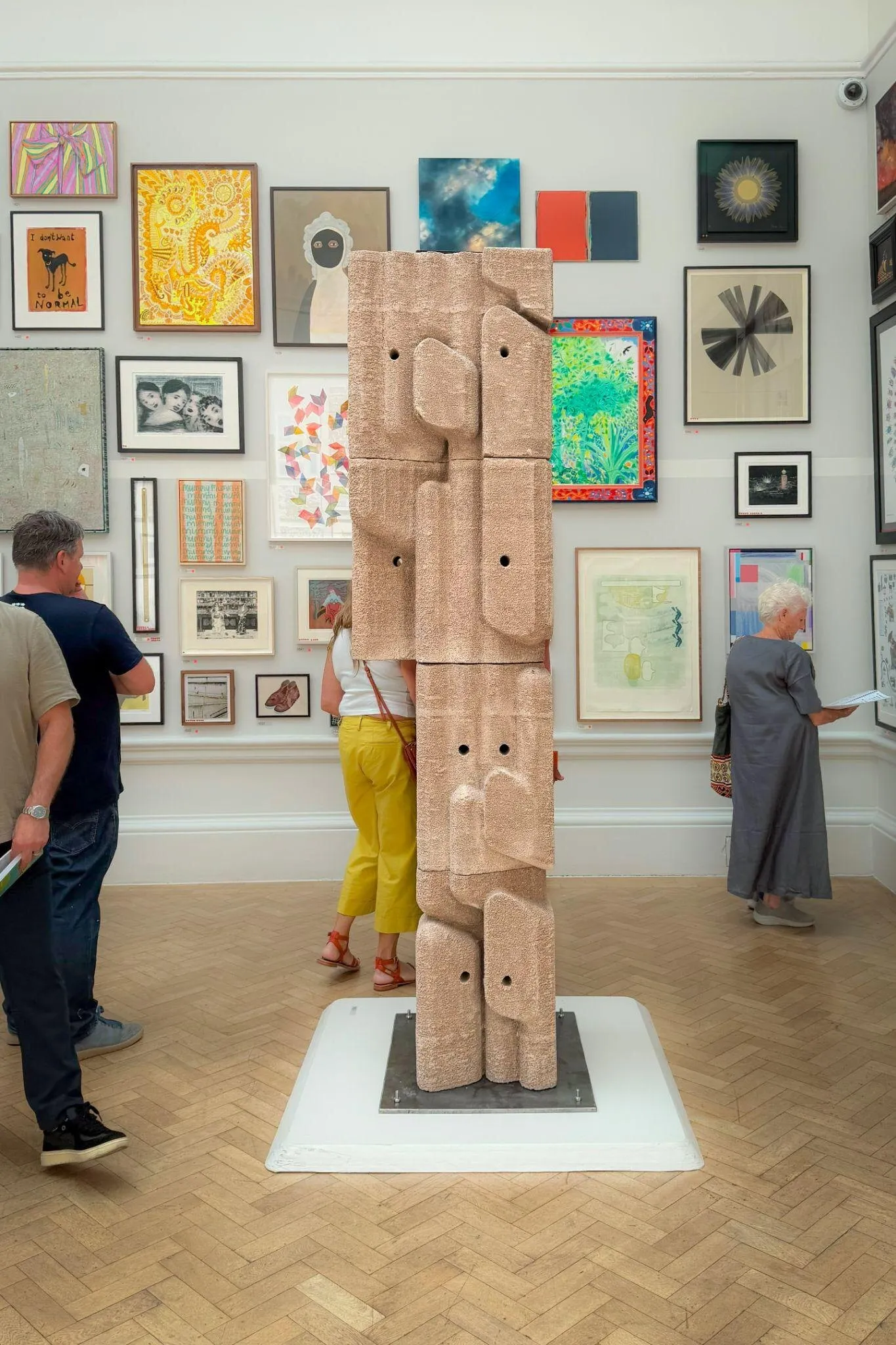 A printed stone column in a gallery hung with paintings